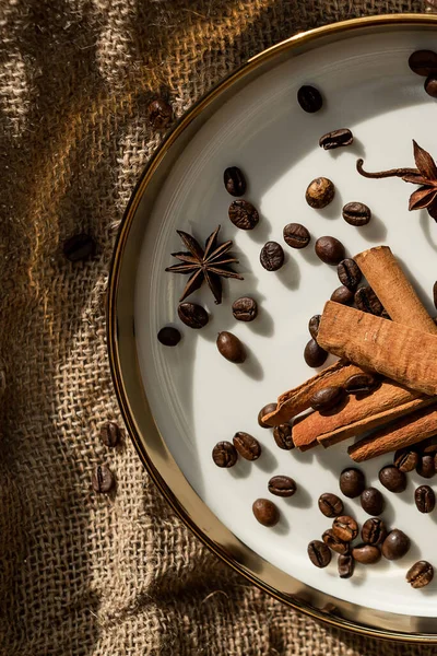 Altın bir tabakta tarçın ve anason, kahve çekirdekleri ve çuval bezi. Sert doku ve baharat kompozisyonu. Kurumuş çiçeklerle. Şekerleme, fırın ve Noel kartlarında kullanılıyor.