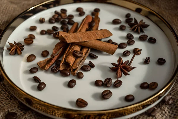 Altın bir tabakta tarçın ve anason, kahve çekirdekleri ve çuval bezi. Sert doku ve baharat kompozisyonu. Kurumuş çiçeklerle. Şekerleme, fırın ve Noel kartlarında kullanılıyor.