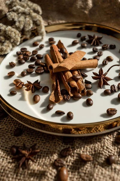 Altın bir tabakta tarçın ve anason, kahve çekirdekleri ve çuval bezi. Sert doku ve baharat kompozisyonu. Kurumuş çiçeklerle. Şekerleme, fırın ve Noel kartlarında kullanılıyor.