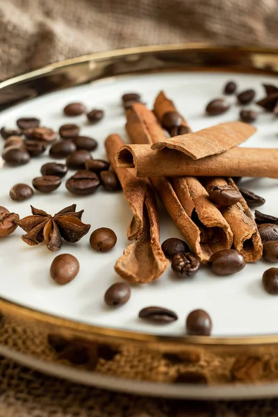 Altın bir tabakta tarçın ve anason, kahve çekirdekleri ve çuval bezi. Sert doku ve baharat kompozisyonu. Kurumuş çiçeklerle. Şekerleme, fırın ve Noel kartlarında kullanılıyor.