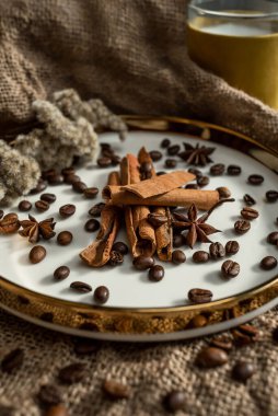 Mumların zarif bir kompozisyonu, baharatların bulunduğu altın kenarlı tabaklar - anason, tarçın ve kahve çekirdekleri. Çuval bezinin arka planına karşı
