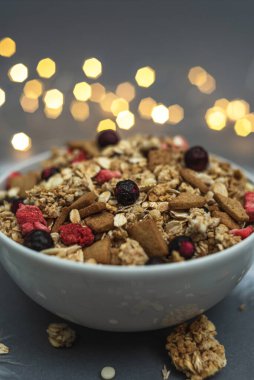 Gri tek renkli arka planda beyaz tüylü ve çelenk kenarlı bir kase müsli. Sağlıklı yemek, sağlıklı kahvaltı.