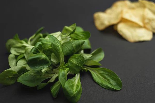 Salatblätter Und Chips Auf Schwarzem Hintergrund Gesunde Und Ungesunde Ernährung — Stockfoto
