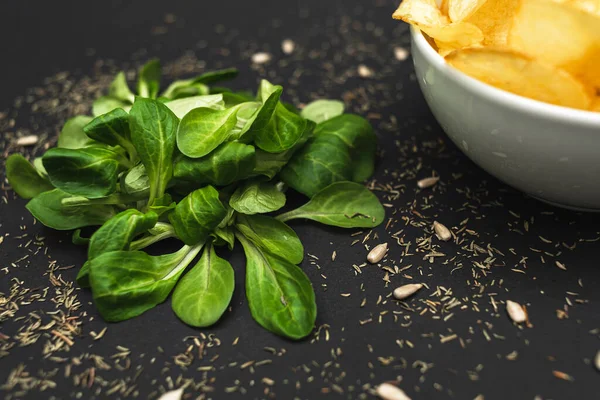 Salatblätter Und Eine Schüssel Chips Auf Schwarzem Hintergrund Gesunde Ernährung — Stockfoto