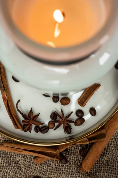 stock image Aesthetic composition of candles, anise, cinnamon sticks and coffee beans on a background of burlap, decorated with dried flowers