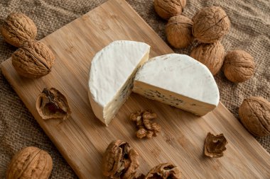 Çuval bezi arka planında bambu tahtasında beyaz ve yeşil küflü ve cevizli kesilmiş peynir kafasının bileşimi