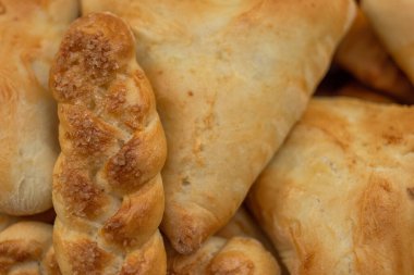 Altın kabuklu, üçgen şekilli ve at kuyruklu taze pişmiş turtalar ve çörekler.