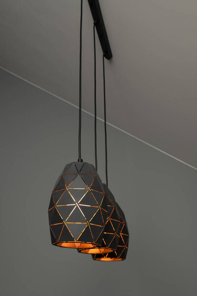 Черные лампы с геометрическим узором, три лампы на черном фоне, горящие теплым светом, с графическим узором