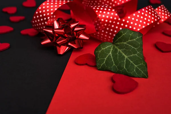 Black and red background with a red ribbon, a sprig of ivy and hearts. Banner with a place for the inscription