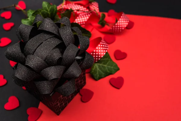 The banner is black and red, with a black gift box and a black bow, decorated with a red polka dot ribbon