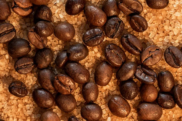 Coffee beans on brown sugar cane, lying on a bronze plate, against a background of coarse burlap. Background picture in brown tones
