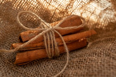 A bunch of cinnamon sticks and anise stars on burlap. Dried flowers and pieces of bark