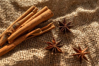 A bunch of cinnamon sticks and anise stars on burlap. Dried flowers and pieces of bark