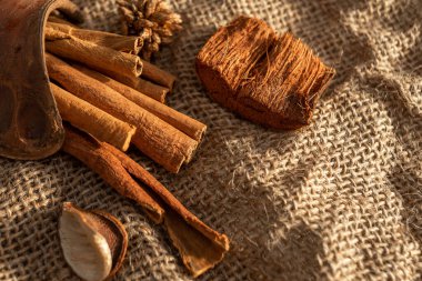 A bunch of cinnamon sticks and anise stars on burlap. Dried flowers and pieces of bark