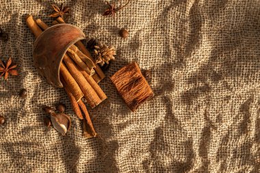 A bunch of cinnamon sticks and anise stars on burlap. Dried flowers and pieces of bark
