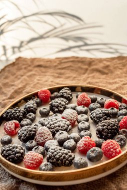 Raspberries and blackberries on a platter, sprinkled with powdered sugar. Healthy food on a plate