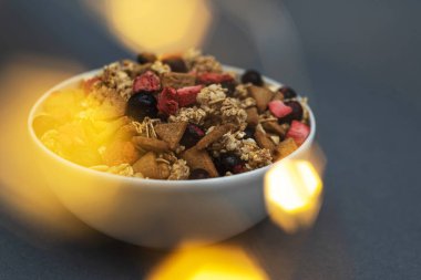 A bowl of muesli on a gray monochrome background, healthy food, healthy breakfast. With the glare of lights from the garland