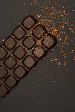 Bitter chocolate bar on a black paper background, close-up. View from above