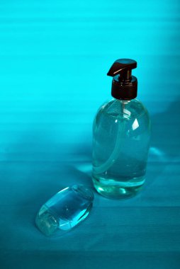 Mavi şeffaf sıvı sabun şişesi ve mavi arkaplanda izole edilmiş bir cep antiseptik jeli. 