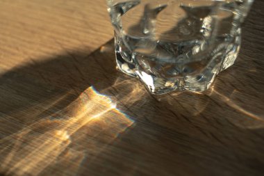 Bir bardak su bir gökkuşağı yaratır. Gökkuşağı kırılması olan bulanık desenli bir masa. Işık ve gölge dumanı kopyalama alanı soyut arkaplan.