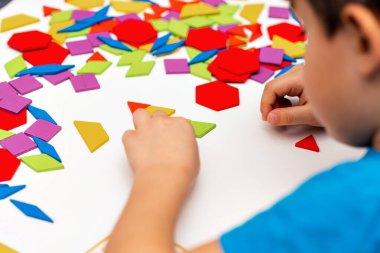 Parlak ahşap tangram oyuncağı oynayan çocuk elleri yakın plan. Çocuk ahşap parmaklık desenleri topluyor. Yaratıcı bebek yeni formlar yapar.