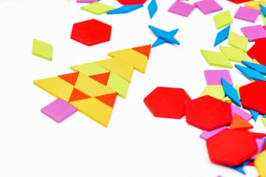 Parlak ahşap tangram oyuncağı oynayan çocuk elleri yakın plan. Çocuk ahşap parmaklık desenleri topluyor. Yaratıcı bebek yeni formlar yapar.