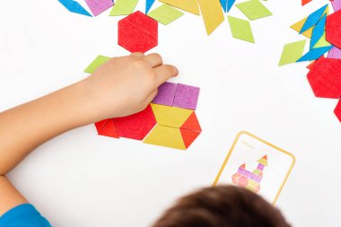 Parlak ahşap tangram oyuncağı oynayan çocuk elleri yakın plan. Çocuk ahşap parmaklık desenleri topluyor. Yaratıcı bebek yeni formlar yapar.