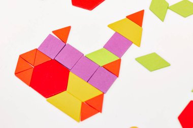 Parlak ahşap tangram oyuncağı oynayan çocuk elleri yakın plan. Çocuk ahşap parmaklık desenleri topluyor. Yaratıcı bebek yeni formlar yapar.