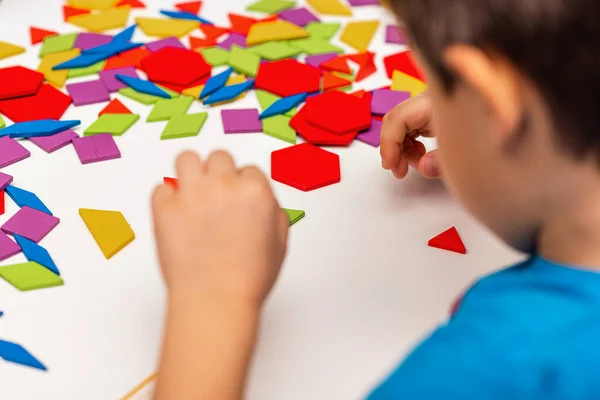 stock image Close up of kid hands playing bright wooden tangram toy. The child collects a pattern of wooden bars. Creative baby make new forms.