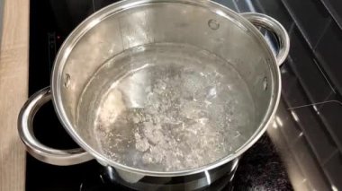 Çorba yapma süreci. Ev mutfağında yemek pişirmek için gerekli malzemeler bir tencereye konur. Kadının elleri kapalı.