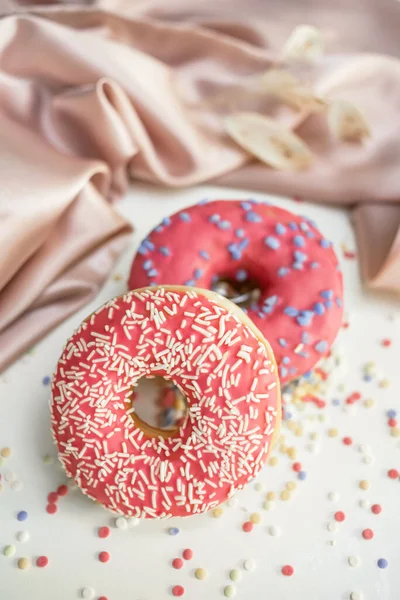 Два Свежих Сладких Пончика Глазурью Столе Фон Украшен Драпированной Тканью — стоковое фото