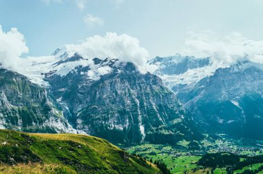 Yeşil çimenler ve dağ zirveleriyle yaz dağı manzarası. İsviçre Alpleri