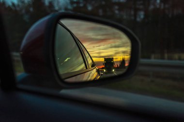 Dikiz aynasından yansıyan yol, bir arabanın dikiz aynasında gün batımı.