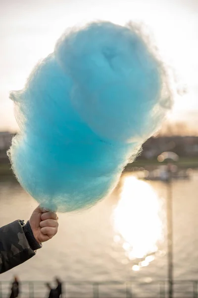 Stock image The hands of a child holding a blue cotton candy in the background of the blue sky