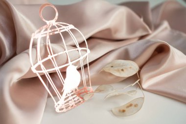 Üzerinde pembe ipek kumaştan yapılmış arka planda bir kuş olan pembe kağıt kafes. Yazı için arka plan fotoğrafı. Tebrik ederim.