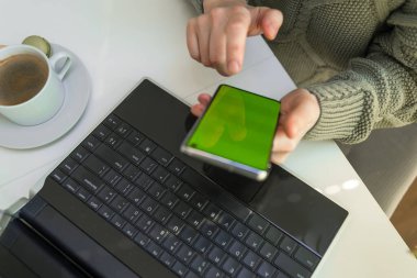 Evde akıllı telefonları kontrol etmek için dizüstü bilgisayar kullanan kadınların ellerini kapat. Merkez ofis. Kadın yakın plan telefon kullanıyor.