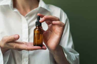 Gerekli yağ, kopyalayacak yeri olan bir kadının elinde bir pipet. Bir şişe yağ ve pipetle kadın eli. Güzellik küresi.
