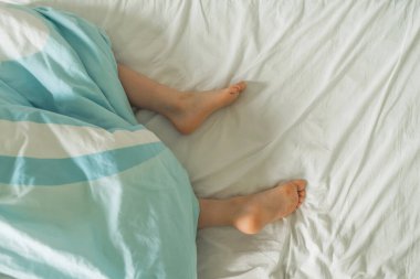 Çocukların bacakları battaniyenin altından sarkıyor. Çıkıntılı bacaklı bir çocuk yatağı. Güzel bebek topukları ve ayak parmakları