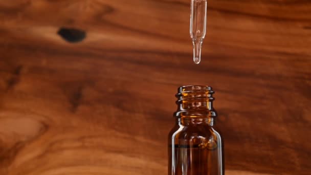 木製の背景にスキンケアのための化粧品油のボトル 薬用油でピペットを保持します 代替医療 ビタミンCとスクワレン 美容液 ヒアルロン酸 ダークブラウンのガラス — ストック動画