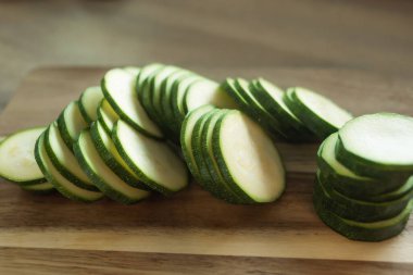 Dilimlenmiş kabak. Tahta bir tahtanın üzerinde kabak kupaları. Yemek hazırlama. Kesme tahtasında çiğ kabak.