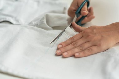 Kısa kot pantolon. Beyaz kot, mezura, makas, masa. Kotlar kesiliyor. Evde şort yapıyorum.
