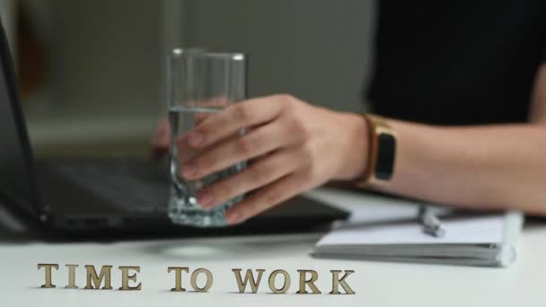 题词是时候工作了 在背景中 一个女人在笔记本电脑前工作 用杯子来暂停和喝水 他继续在键盘上打字 — 图库视频影像