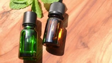 Brown and green bottles of essential oils. natural cosmetics for skin care. A bottle and fresh mint on a wooden table. Taking care of health and beauty.