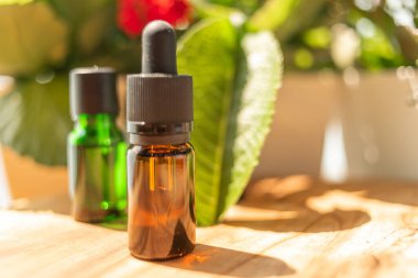 Önemli yağ şişeleri. Cilt bakımı için doğal kozmetik ürünleri. Ahşap bir masada bir şişe ve çiçekler. Sağlık ve güzellikle ilgilenmek. Cilt bakımı için doğal kozmetikler.