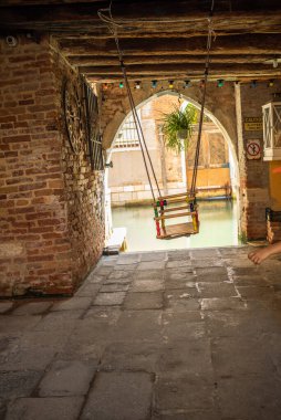 Çocuklar bir Venedik evinin avlusunda sallanıyorlar. Evin kemerini suyun arka planında salla. Güzel arkaplan resmi