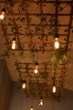 Bitkilerle süslenmiş ahşap örgüden yapılmış modern bir lamba. İç aydınlatmanın modern tasarımı