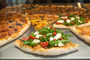 Bir kafede bir dilim pizzanın yakın çekimi. Pizzacıda hazır pizza satışı var. İtalyan pizzası ve roka.