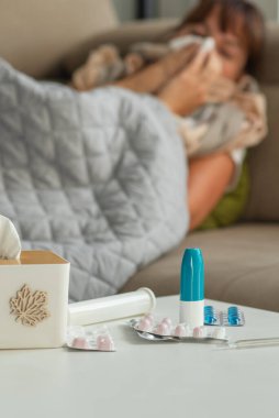 Hasta, orta yaşlı, hapşıran, burnu akan, mendil tutan, yatağa oturan, hasta, soğuk algınlığına yakalanmış, grip olmuş, grip salgını belirtileri gösteren, evde tek başına ilaç alan bir kadın.