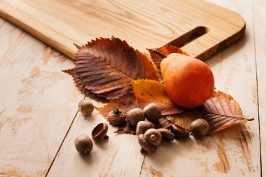 Armut, sarı yapraklar, meşe palamudu ve bir kesme tahtası...