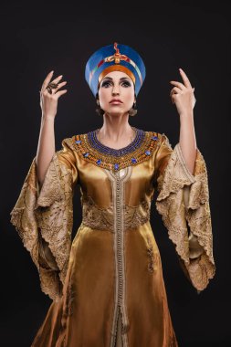 Kraliçe Kleopatra, taç, kolye görünümünde kahverengi gözlü ve akşam makyajlı güzel bir kadının yakın plan stüdyo portresi.